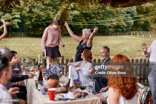 family and friends having on outdoor celebration - senior man dancing on table stock pictures, royalty-free photos & images