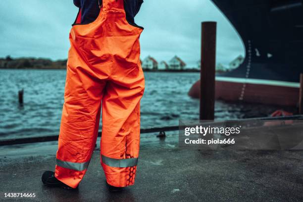 woman fisherman at harbor with fishing boat - waterproof clothing stock pictures, royalty-free photos & images