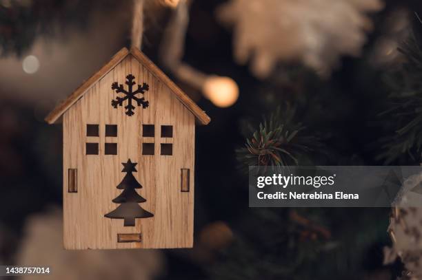 wooden toy house with windows on the green branch of the christmas tree. background space for copying. christmas and new year. christmas mortgage - homeowners decorate their houses for christmas stockfoto's en -beelden