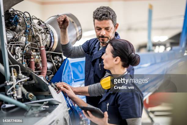 männliche und weibliche flugzeugingenieure untersuchen den motor von luftfahrzeugen - male airport stock-fotos und bilder