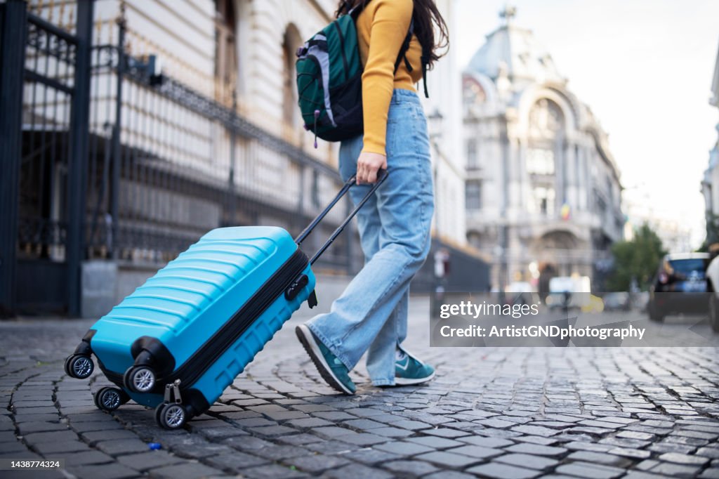 Turista irreconocible caminando por la calle con maleta.