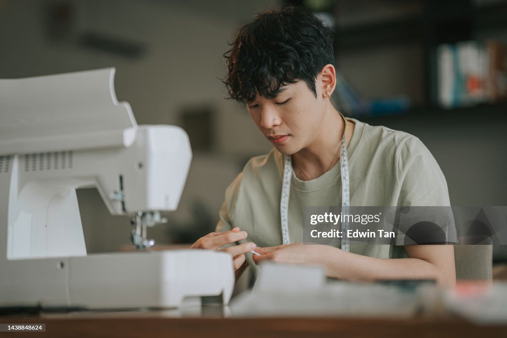 Asian Chinese Gay man sewing with sewing machine at home in living room