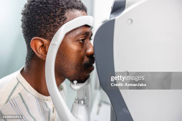 ein afroamerikanischer mann während einer augenarztuntersuchung - astigmatism stock-fotos und bilder