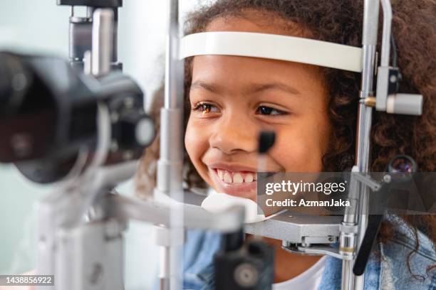 an optometrist checking young girl's vision with trial frame - eye chart stock pictures, royalty-free photos & images