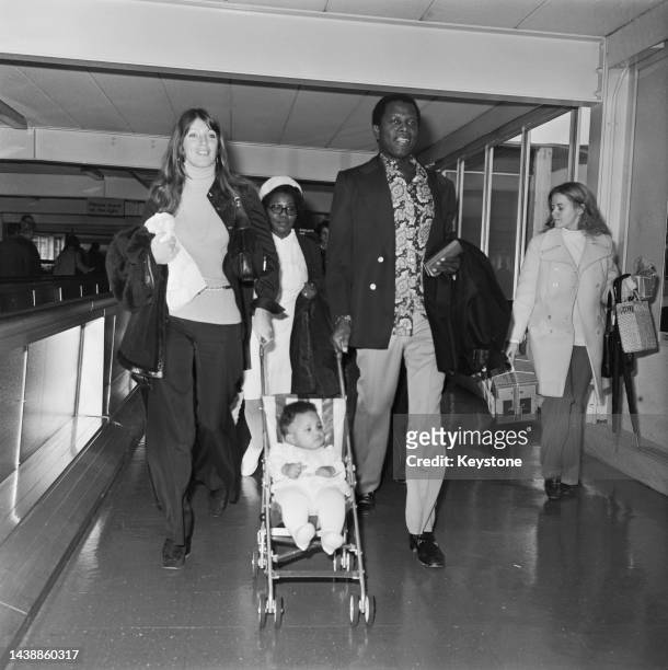 Canadian actress Joanna Shimkus and American actor Sidney Poitier each with a hand on the pushchair carrying their daughter, Anika Poitier, at...