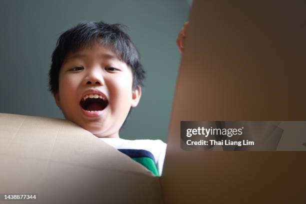 surprised young asian boy looking into a box - child picking up toys stock pictures, royalty-free photos & images