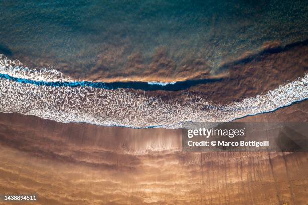 top down view of waves crashing on beach - distrikt set�úbal stock-fotos und bilder