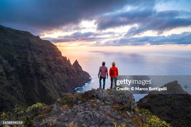 Two Friends Overlooking The Coast At Sunset In Tenerife Spain High-Res Stock Photo