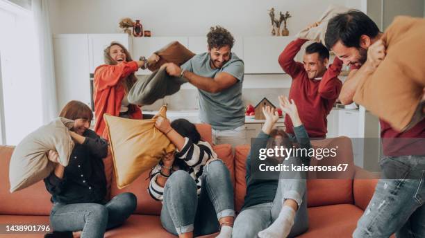 happy friends having a funny pillow fight - battle group stock pictures, royalty-free photos & images