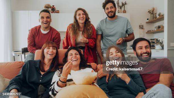 group of friends watching a funny movie tv, eating popcorn and laughing - friends tv show stock pictures, royalty-free photos & images