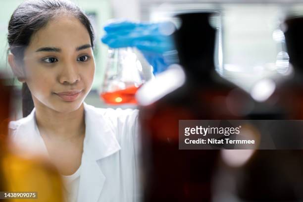 food safety and product development laboratory. asian female scientists analyze solution samples in a beaker for product development in food laboratory testing services. - biochimiste photos et images de collection