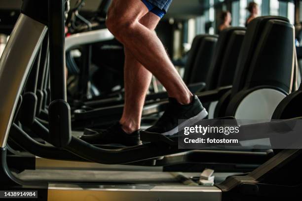 nicht erkennbarer männlicher athlet, der ausdauer und cardio auf einem crosstrainer im fitnessstudio trainiert - cross trainer stock-fotos und bilder