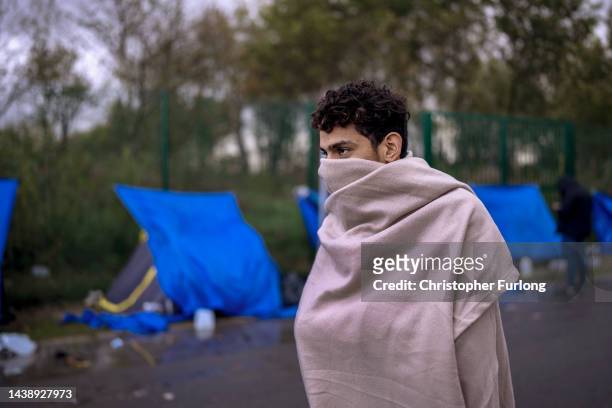 Teenage migrant uses a blanket to try and keep warm at a camp in an industrial zone on November 04, 2022 in Calais, France. Around 2,000 migrants are...