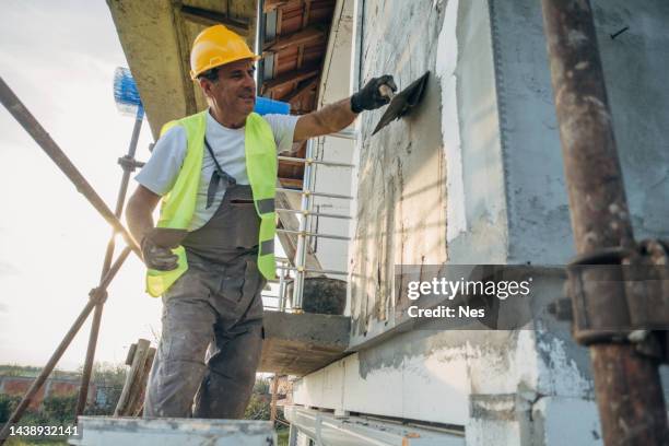 a construction worker builds the facade of a building - rampur bildbanksfoton och bilder