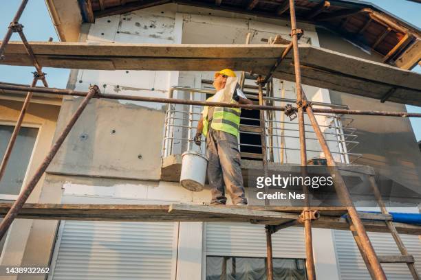 construction worker on scaffolding - house insulation not posing stock pictures, royalty-free photos & images