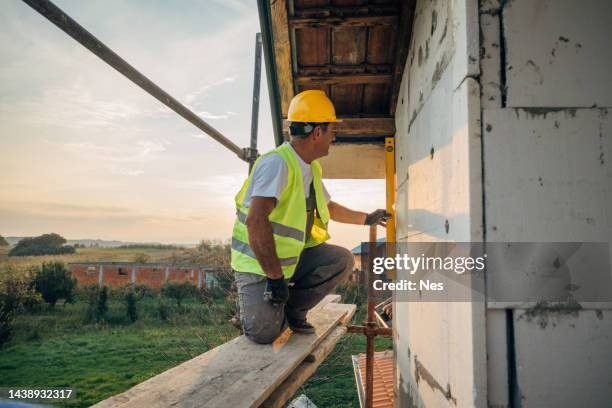 a construction worker is repairing the facade of a building - insulation stock pictures, royalty-free photos & images