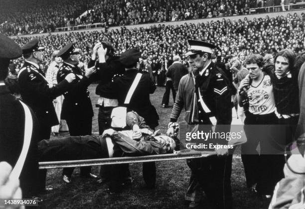 St John Ambulance volunteers carry an injured fan on a stretcher after crowd trouble affected English First Division match between West Ham United...