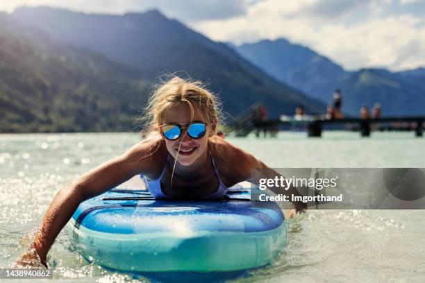 teenager genießen das sup-paddleboard auf dem see in den österreichischen alpen. - mirrored sunglasses stock-fotos und bilder