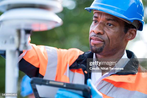 ambient calibration for air quality monitoring device in field operation. male african american meteorologists measure air quality monitoring devices to maintain air quality that is suitable for consumption. - measuring potential business stock pictures, royalty-free photos & images