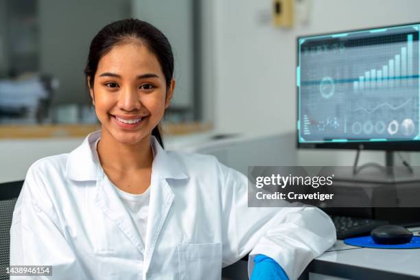 female asian scientist or chemist working in an environmental laboratory with a computer data analysis of research data that show with digitization display. laboratory with data management. - young scientist stock pictures, royalty-free photos & images