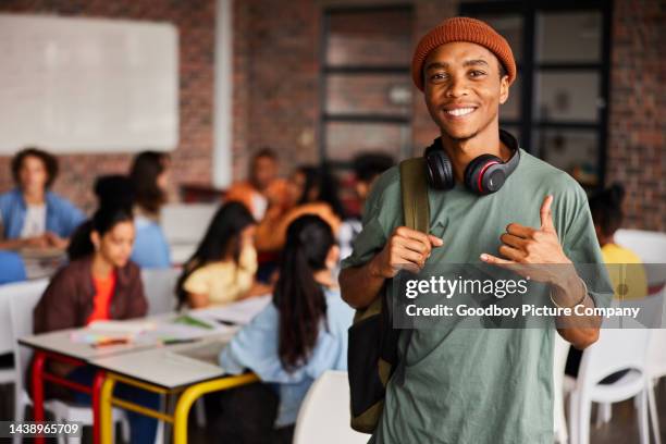 smiling young male college student doing the shaka sign in a classroom - shaka sign stock pictures, royalty-free photos & images