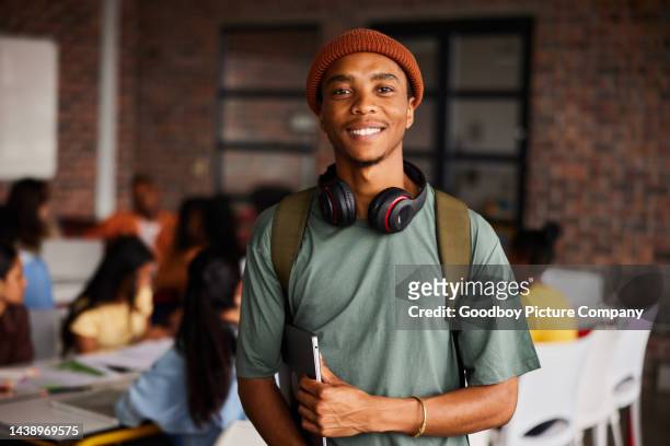 教室に立つヘッドフォンを着た笑顔の若い男子大学生 - bold man ストックフォトと画像