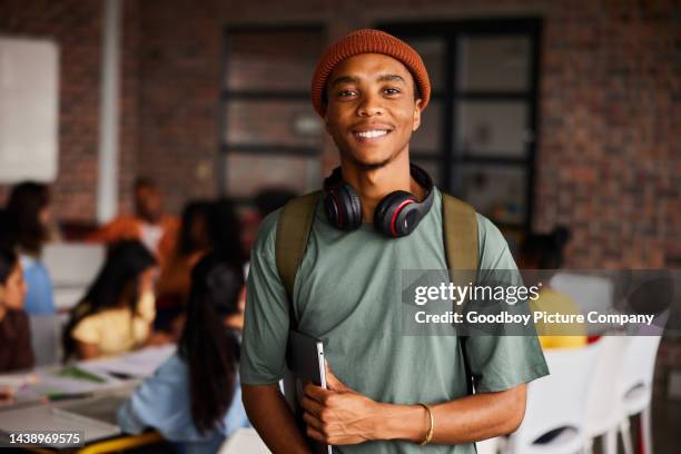 smiling young male college student wearing headphones standing in a classroom - estudante adulto imagens e fotografias de stock