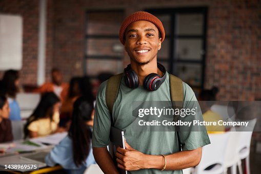 Smiling young male college student wearing headphones standing in a classroom Smiling young male college student wearing headphones standing in a classroom
