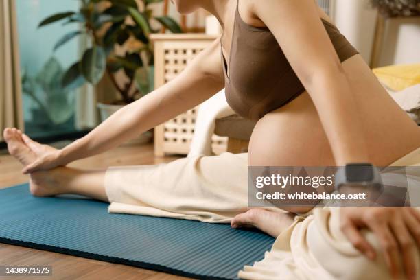 happy calm pregnant woman sit on yoga mat and stretching warm up for yoga practice. - breathing new life stock pictures, royalty-free photos & images