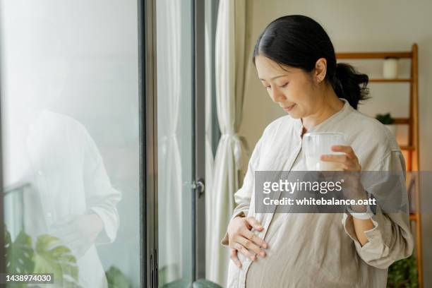 asian beautiful pregnancy woman drink a glass of milk for health care. - vitamins and minerals stock pictures, royalty-free photos & images