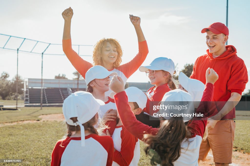 Little league team celebrates winning homerun together with coaches