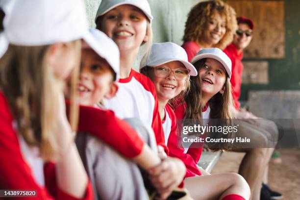little league team has fun together while sitting in dugout during baseball game - youth baseball and softball league stock pictures, royalty-free photos & images