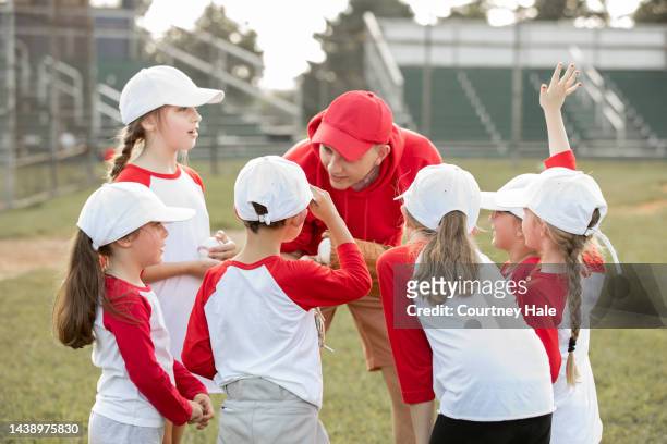 coach huddles with little league baseball team to discuss game - huddle sport girls stock pictures, royalty-free photos & images