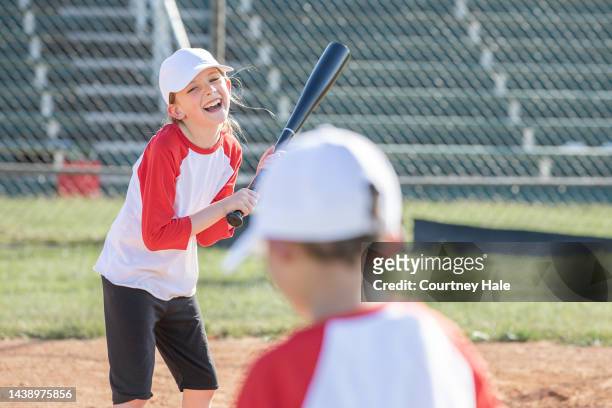 girl laughs while up to bat during little league baseball game - baseball huddle stock pictures, royalty-free photos & images