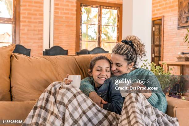 mãe e filha tomando bebida quente no sofá da sala - winter family - fotografias e filmes do acervo