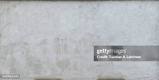front view of a plastered gray stone wall with stains from graffiti removal. - graffiti wall stock-fotos und bilder
