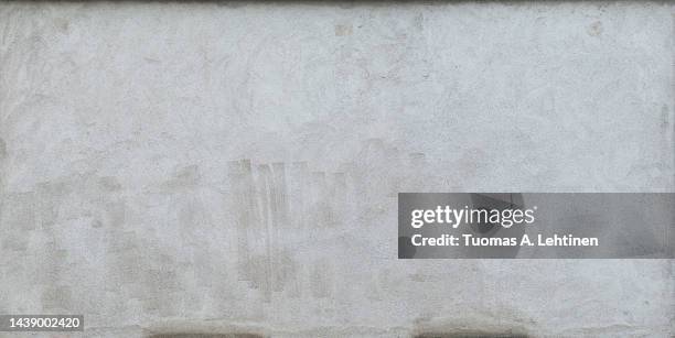 front view of a plastered gray stone wall with stains from graffiti removal. - graffiti wall stockfoto's en -beelden