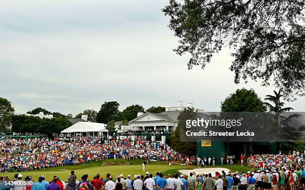 Patrons watch as Lee Westwood of England putts on the 18th green and Phil Mickelson of the United States looks on during the third round of the Wells...