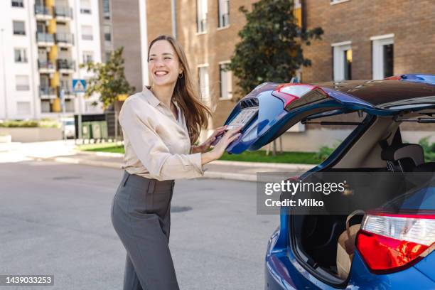 beautiful woman closes the trunk of a car - car trunk closed stock pictures, royalty-free photos & images