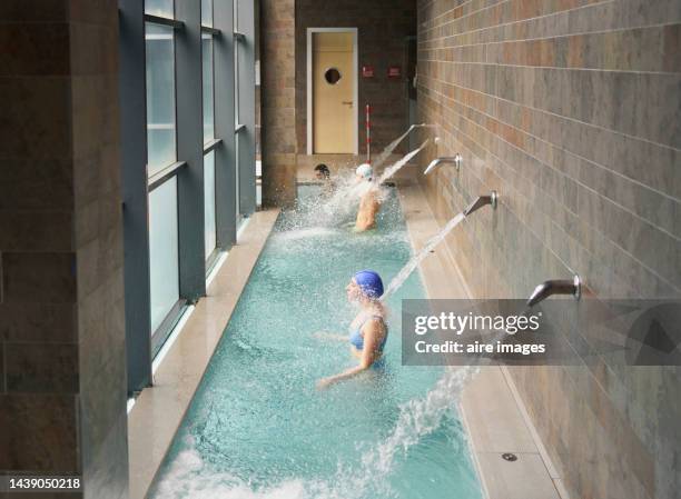 general side view of people under a waterfall jet in health spa - sauna und nassmassage stock-fotos und bilder