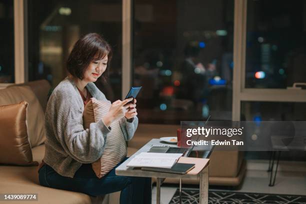 asian chinese woman working on home finance planning at home in living room - time change stock pictures, royalty-free photos & images