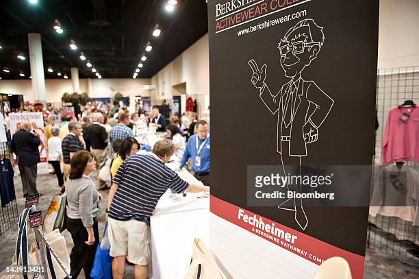 Sign bearing an image of Warren Buffett, chairman of Berkshire Hathaway Inc., sits on display as shareholders shop nearby during the Berkshire...