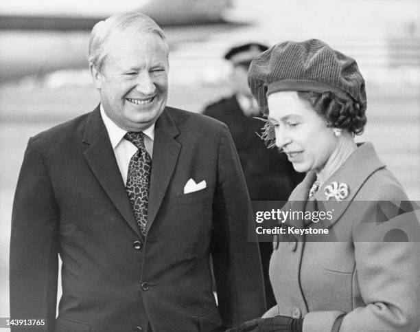 Queen Elizabeth II with British Prime Minister Edward Heath at Heathrow Airport, London, 28th January 1974. The Queen is about to take a flight to...