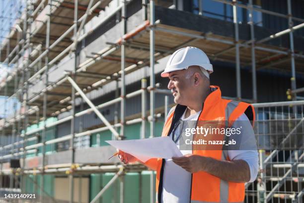 civil engineer holding planning documents at construction site. - real estate developer stock pictures, royalty-free photos & images
