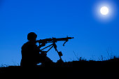 Soldier saluting at sunset and twillight with his rifle