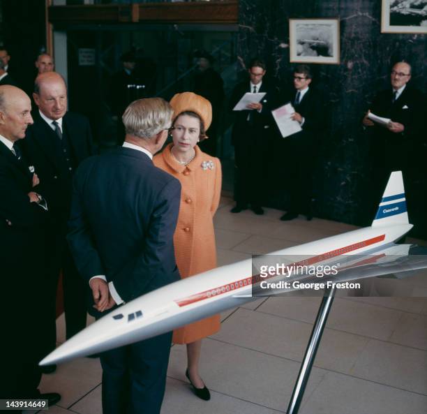 Queen Elizabeth II chatting with businessmen in front of a model of the Concorde airliner, at the British Aircraft Corporation works in Filton,...