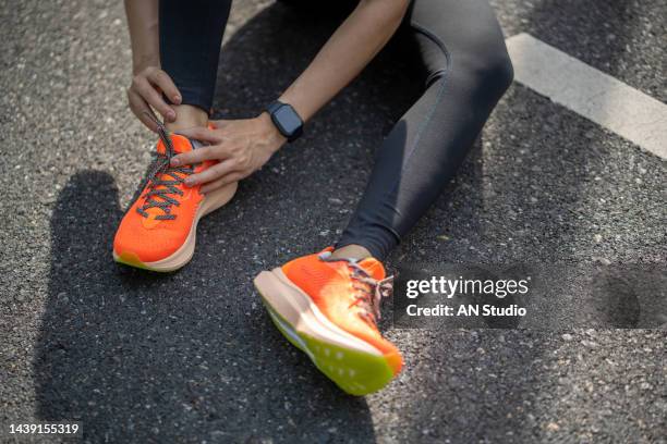 achilles injury on running outdoors. women holding achilles tendon by hands close-up and suffering with pain. ankle twist sprain accident in sport exercise running jogging. - pressão física imagens e fotografias de stock