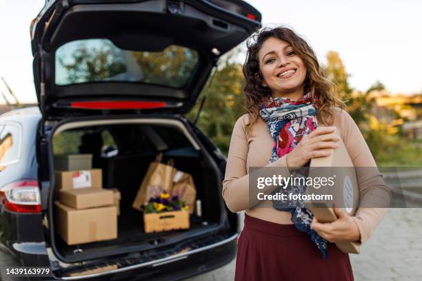 charming mid adult business owner holding a package, smiling at camera with confidence - second hand car stock pictures, royalty-free photos & images