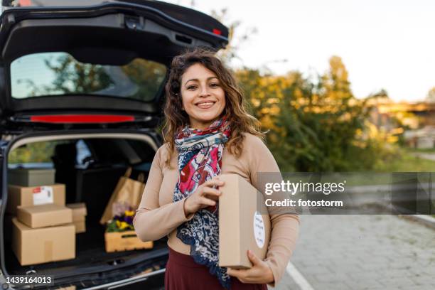 charming mid adult business owner holding a package, smiling at camera with confidence - ecuadorian ethnicity stock pictures, royalty-free photos & images