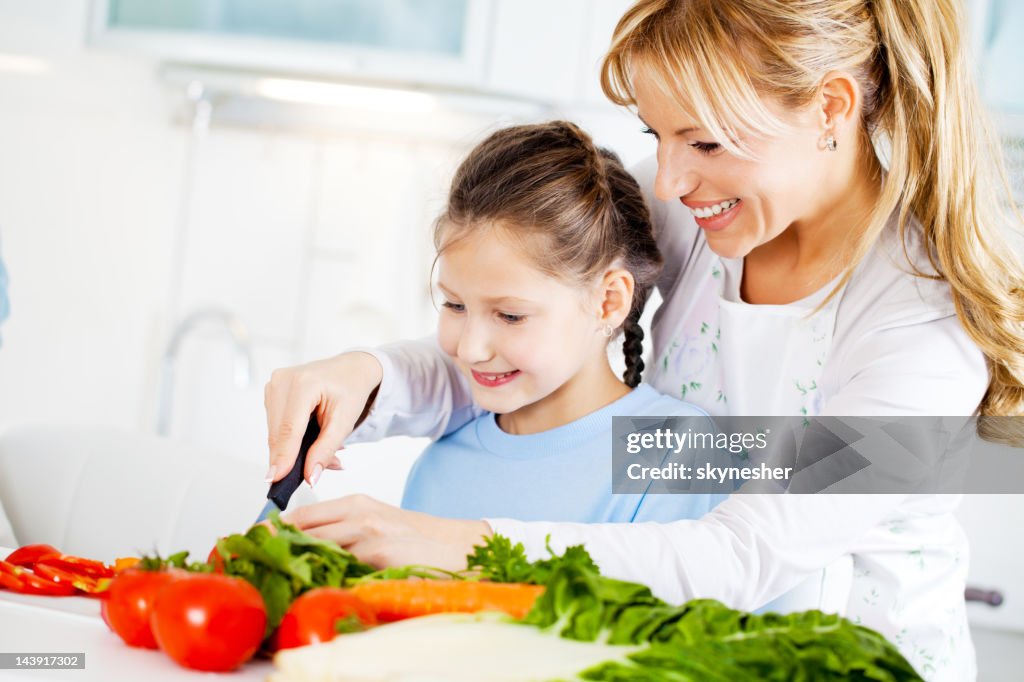 Mother and daughter cutting vegetables in the kitchen.